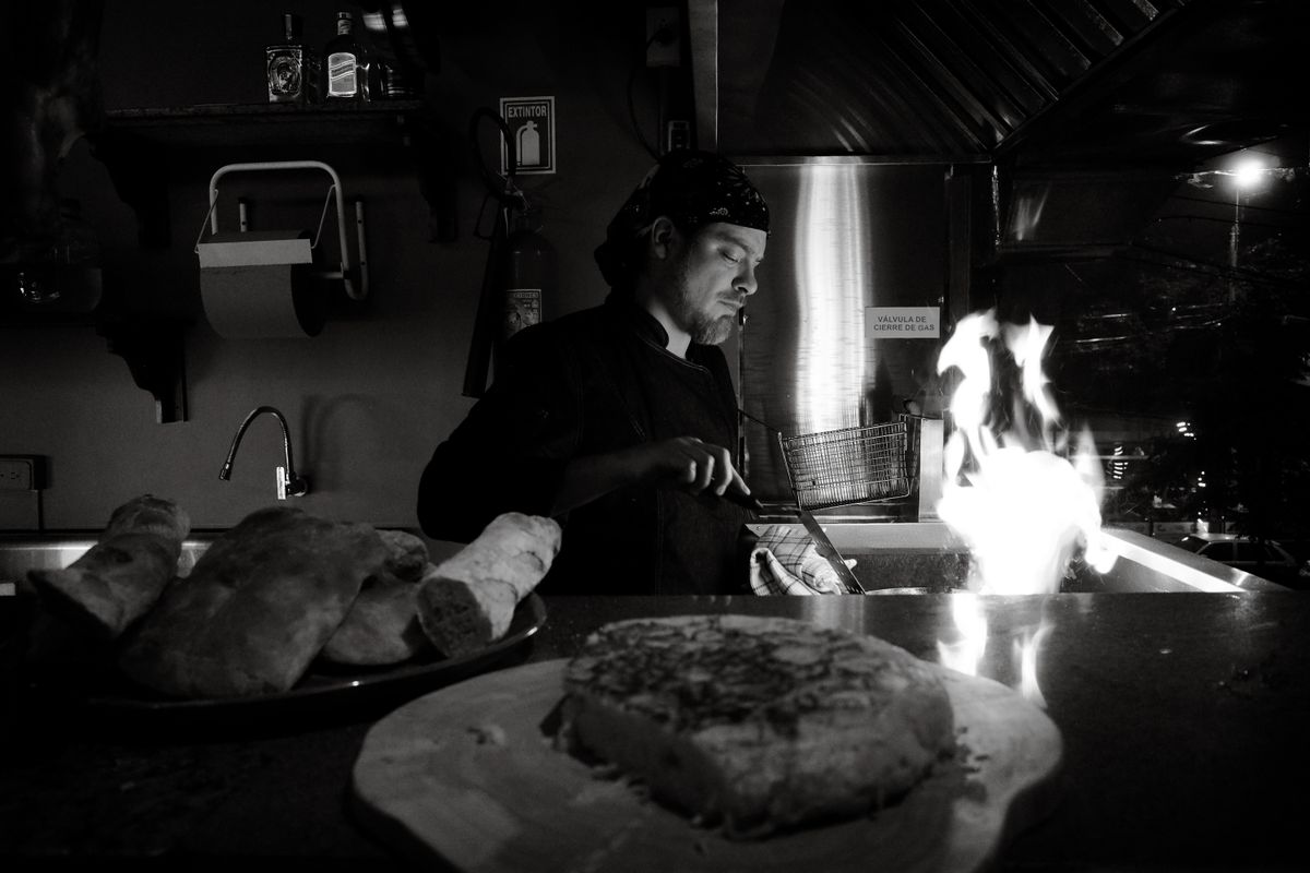 A chef cooking some food next to a flame in a kitchen