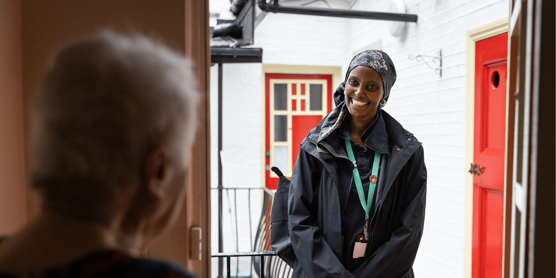 A patient opens the door to her Hospice@Home Healthcare Assistant.