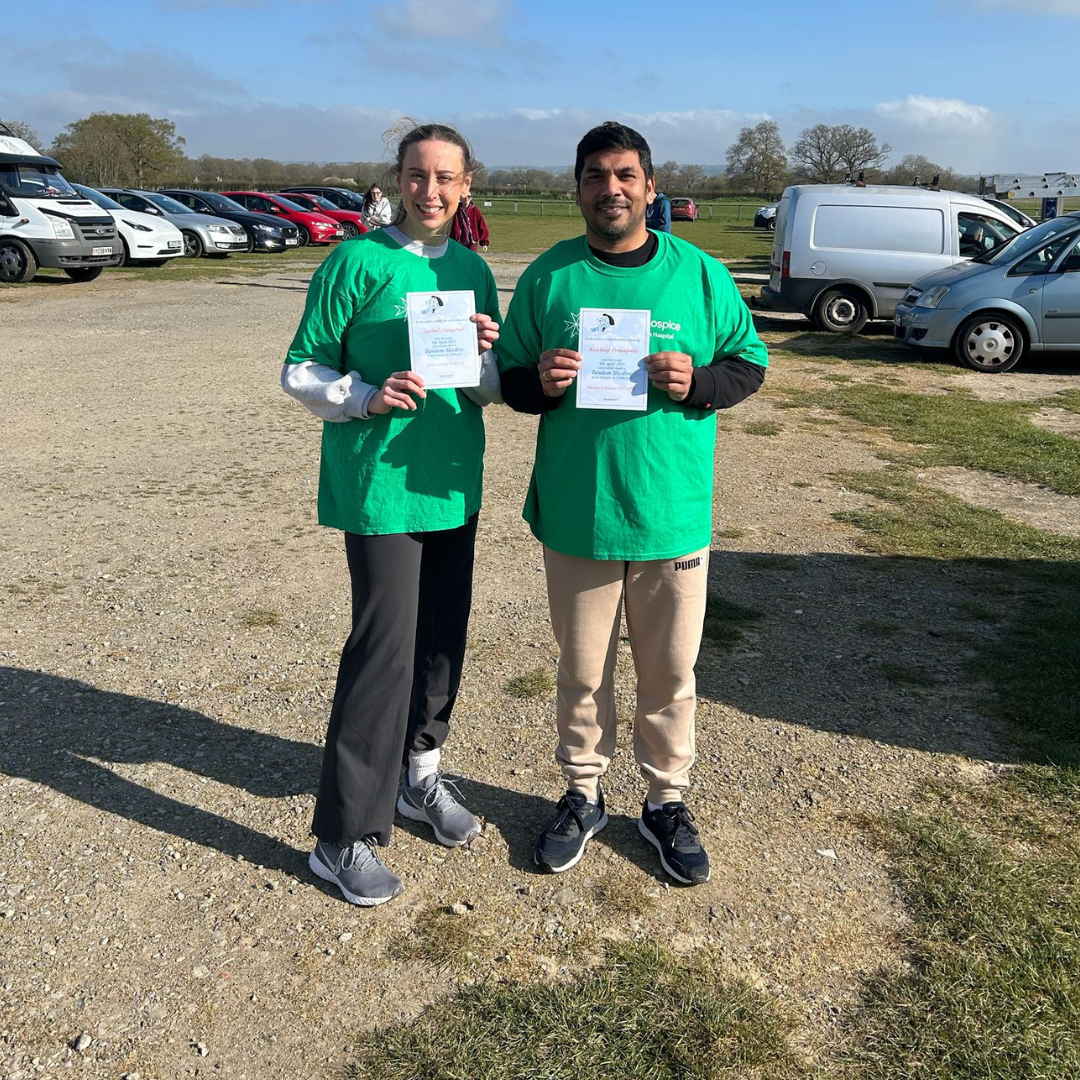 Kuldeep and Isabel holding up their certificates after completing their tandem skydive.