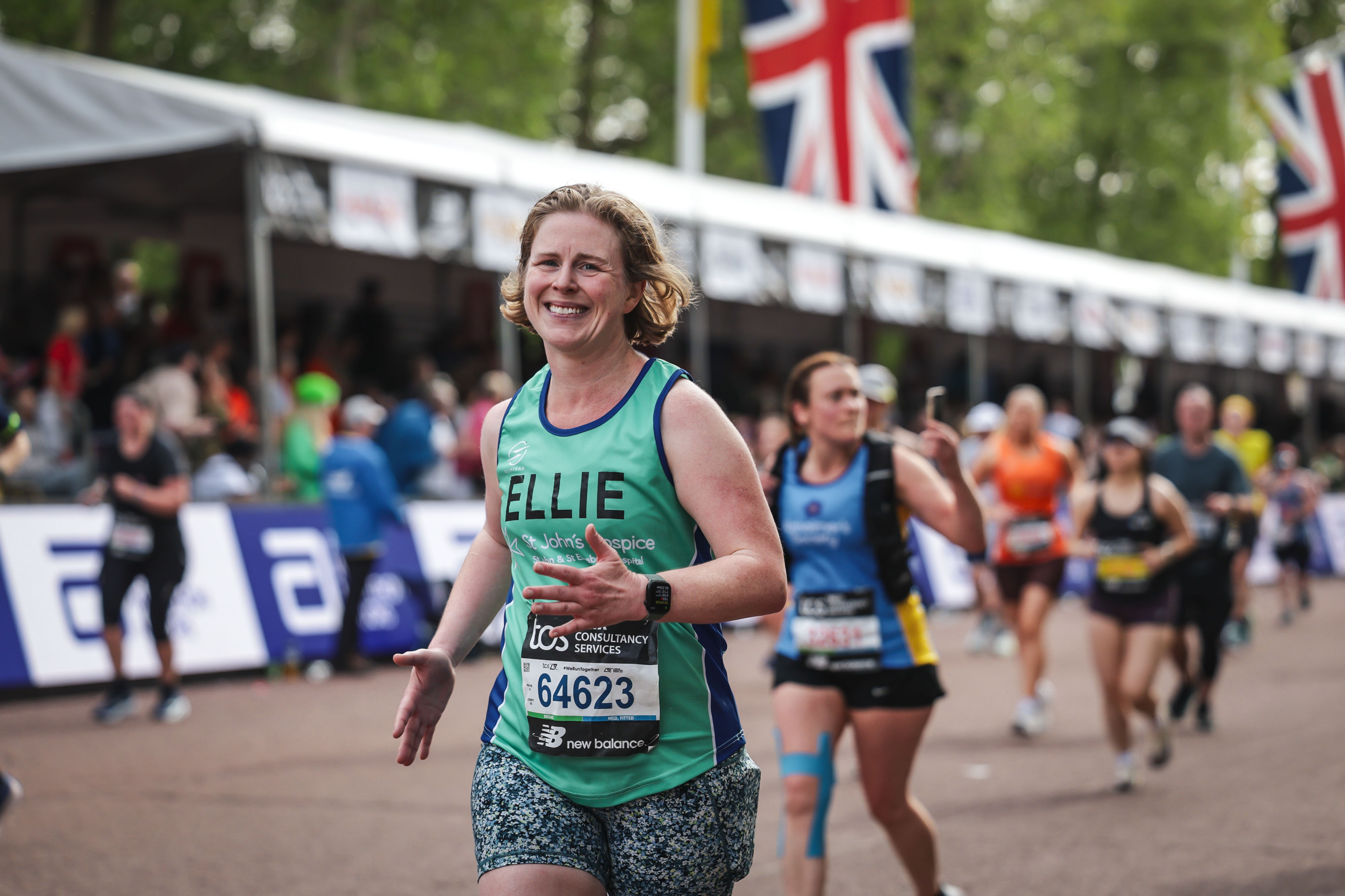 Runner holds his arms up in a cheering pose as he runs past the camera.