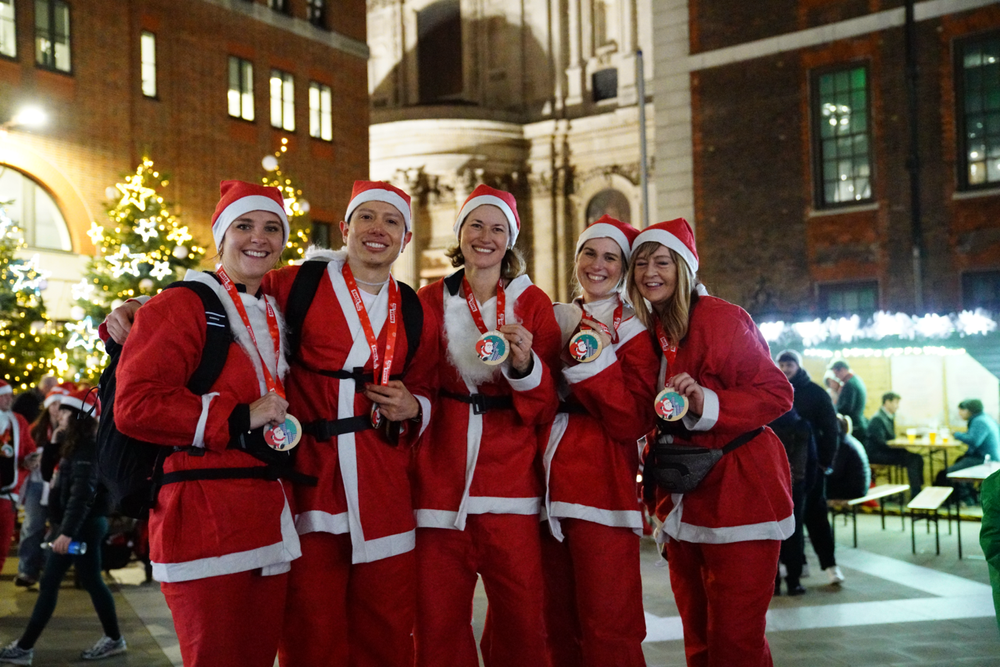 A group of people dressed as santa holding their finisher's medals.