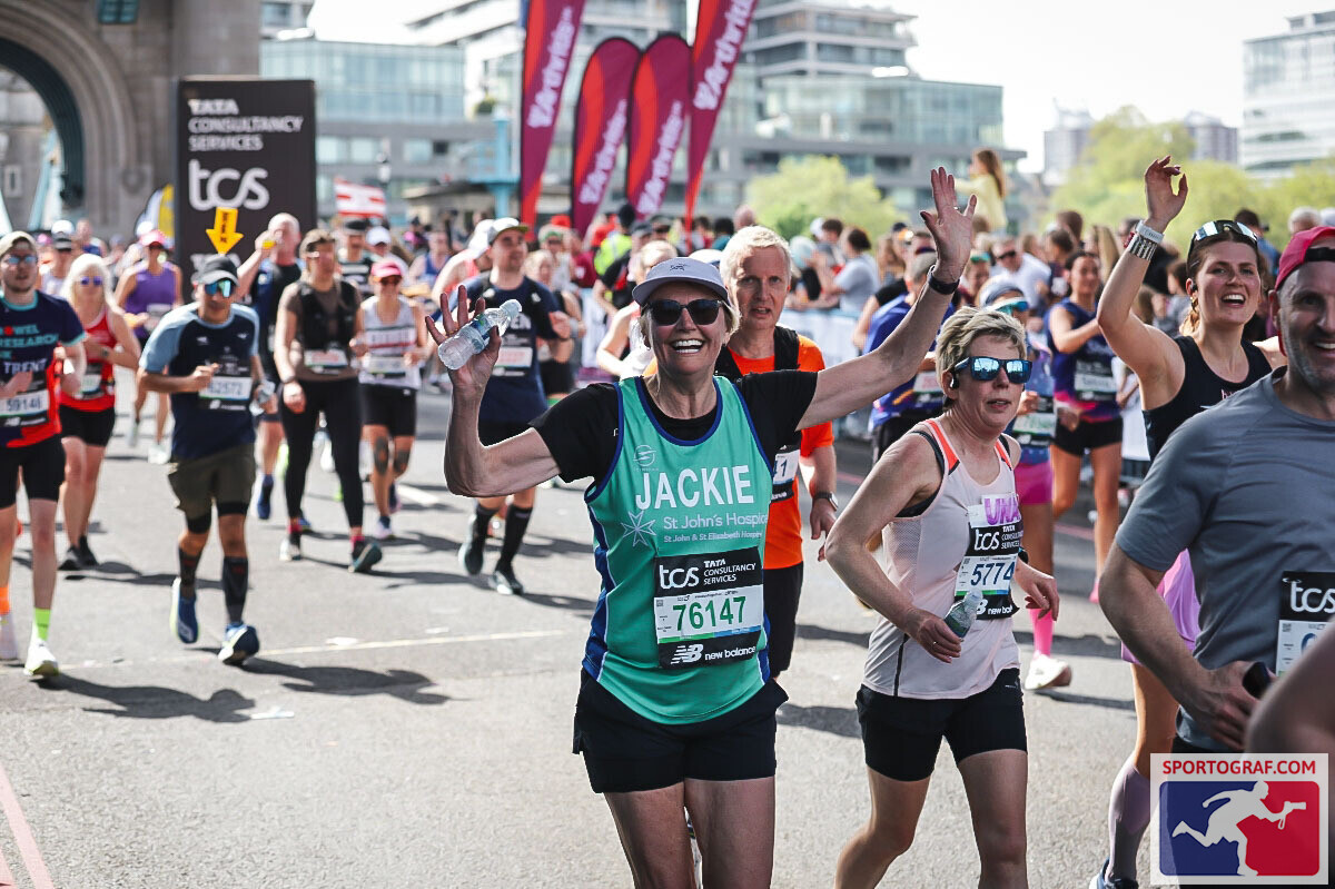 woman smiling, arms in the air, mid race.