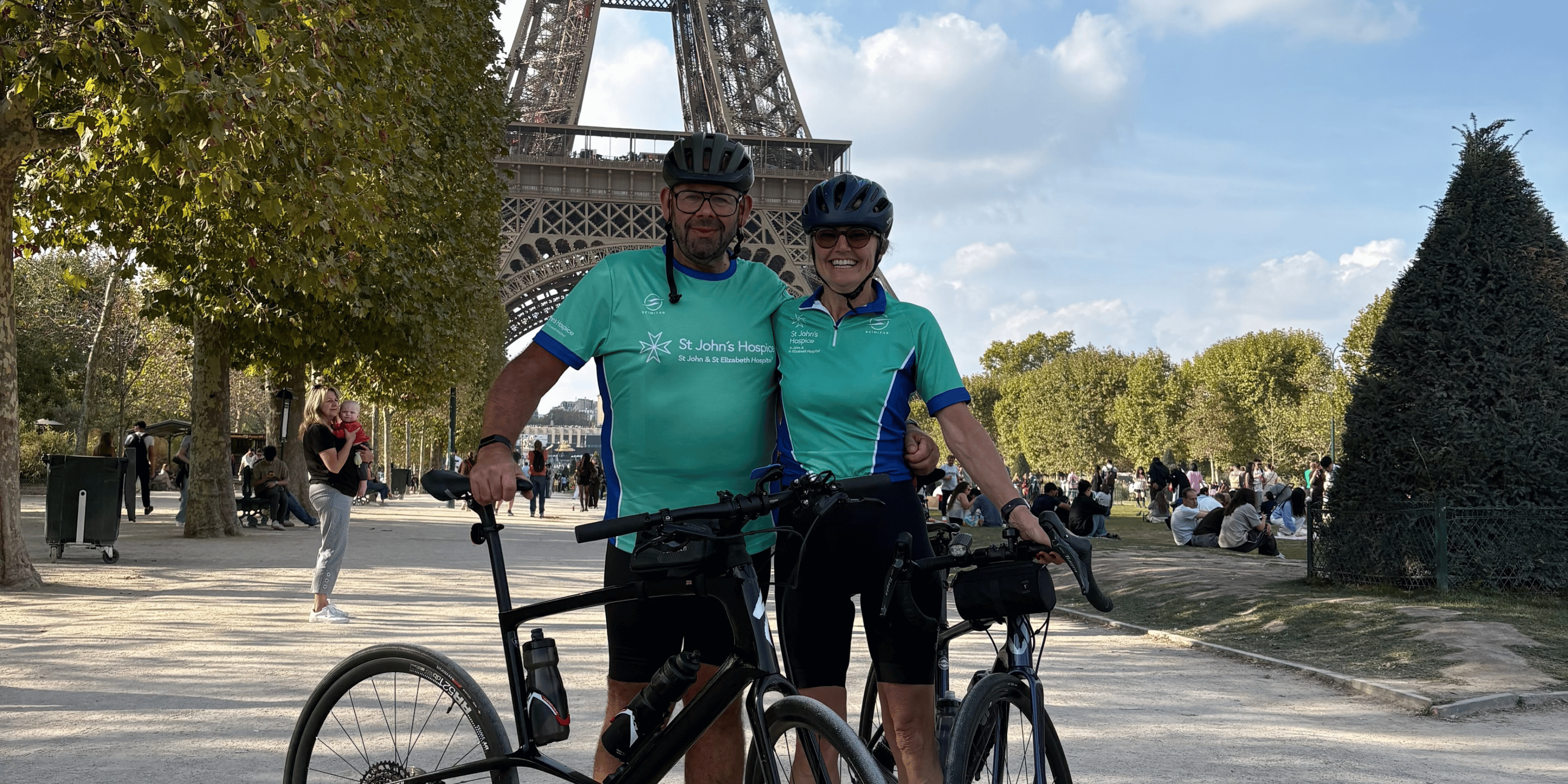 Two cyclists in St John's Hospice tops in front of the Eiffel Tower.