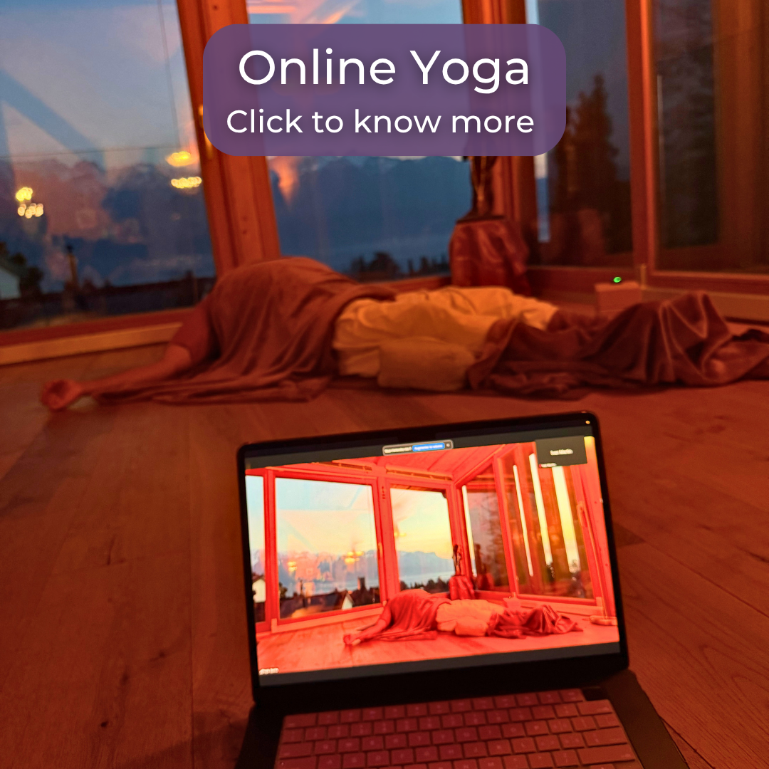 Person in purple shirt doing yoga pose indoors with mats and blocks, mountain view outside windows.