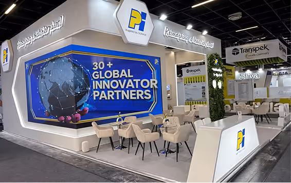 Modern exhibition booth with a large digital screen showing '30+ Global Innovator Partners' and seating area with tables and beige chairs.