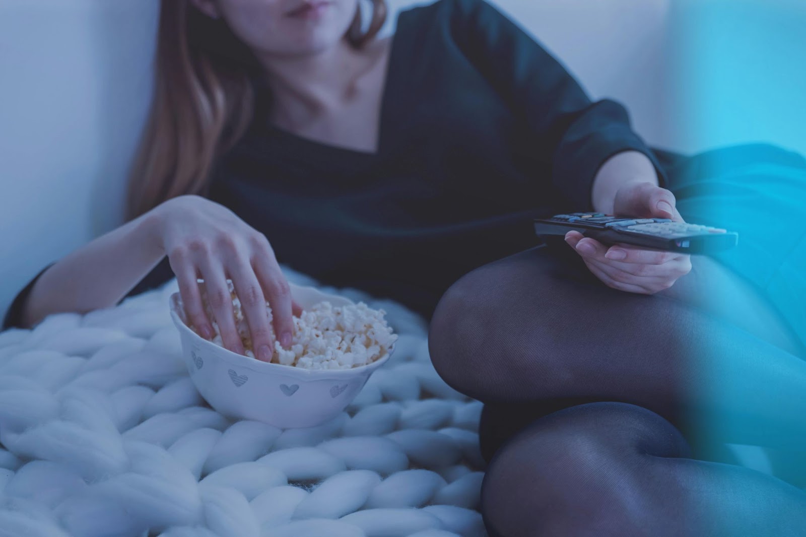 A photo of a person watching TV and eating popcorn