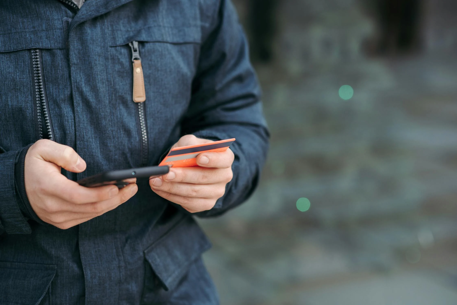 A photo of a person holding a credit card while using their smartphone