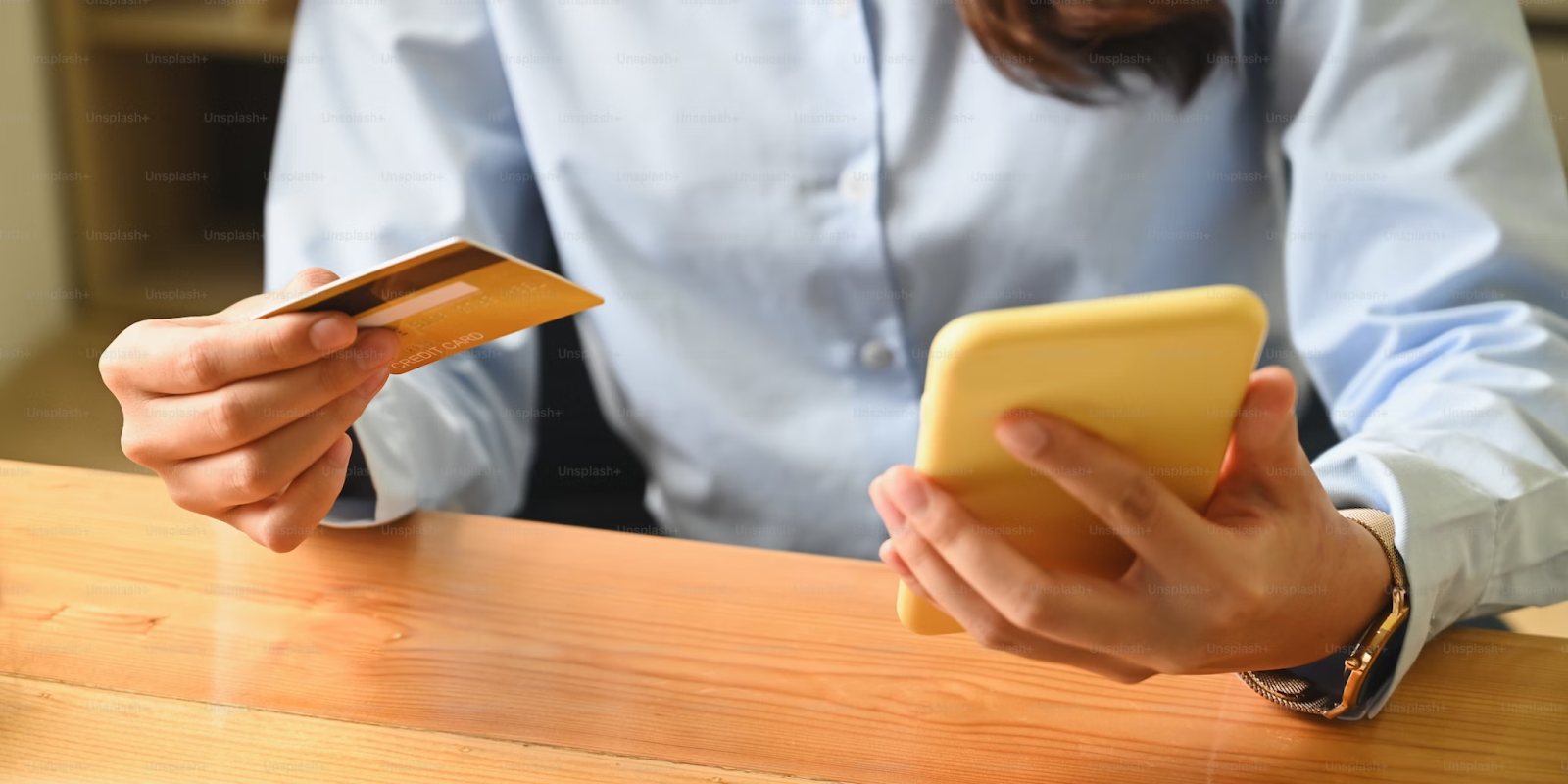 A cropped image of a person holding a smartphone and a credit card in their hands