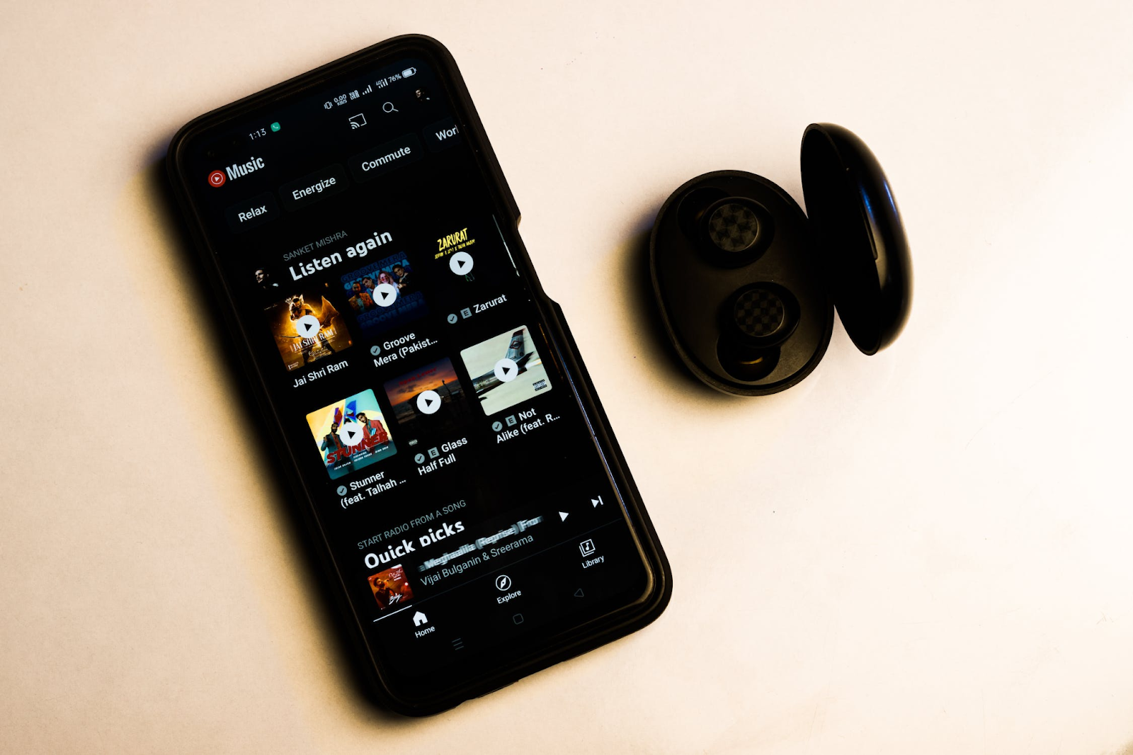 A bird’s eye view of a phone placed next to a pair of earpads and displaying stream songs