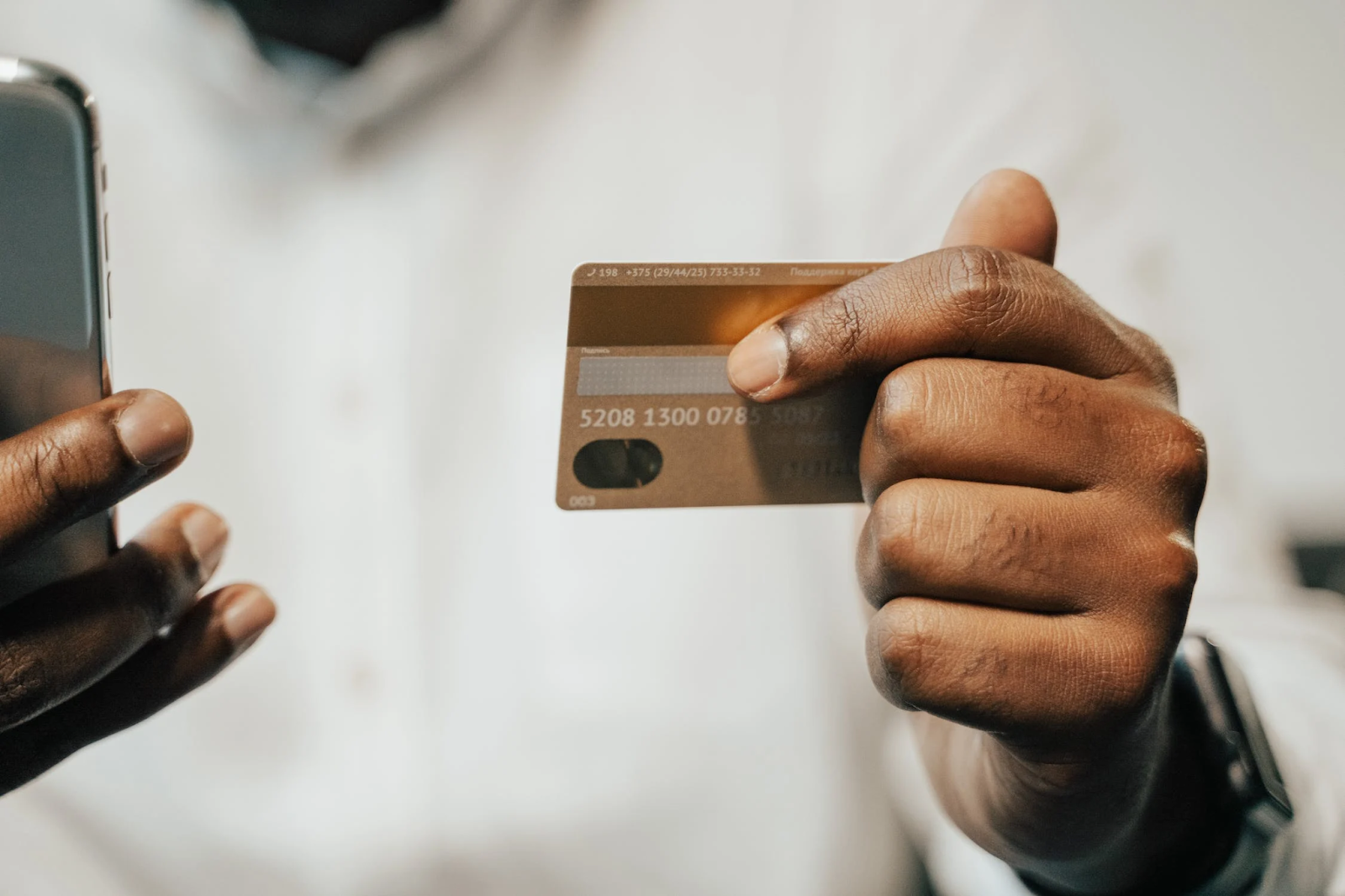 A photo of a person holding a credit card in one hand and a cellphone in the other