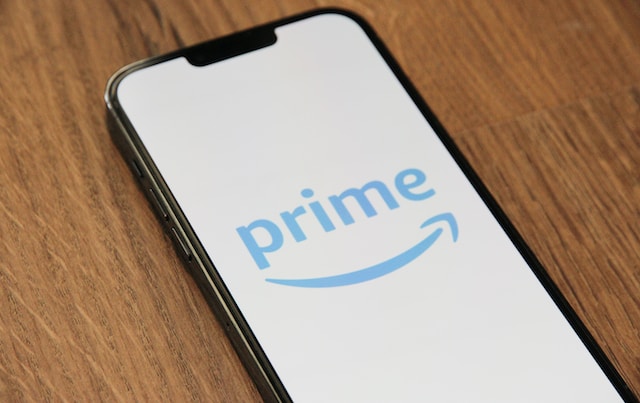 A photo of an iPhone placed on a wooden surface and displaying an Amazon Prime logo