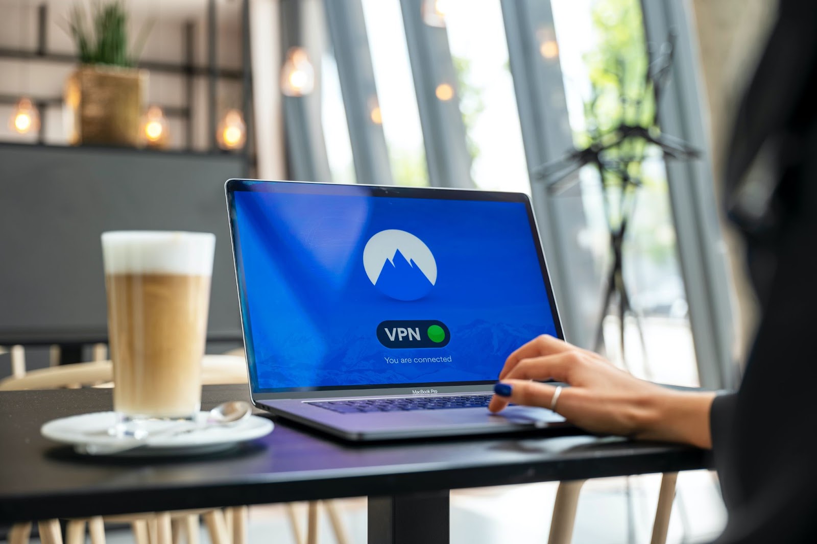 A photo of a person in a café using NordVPN on a laptop