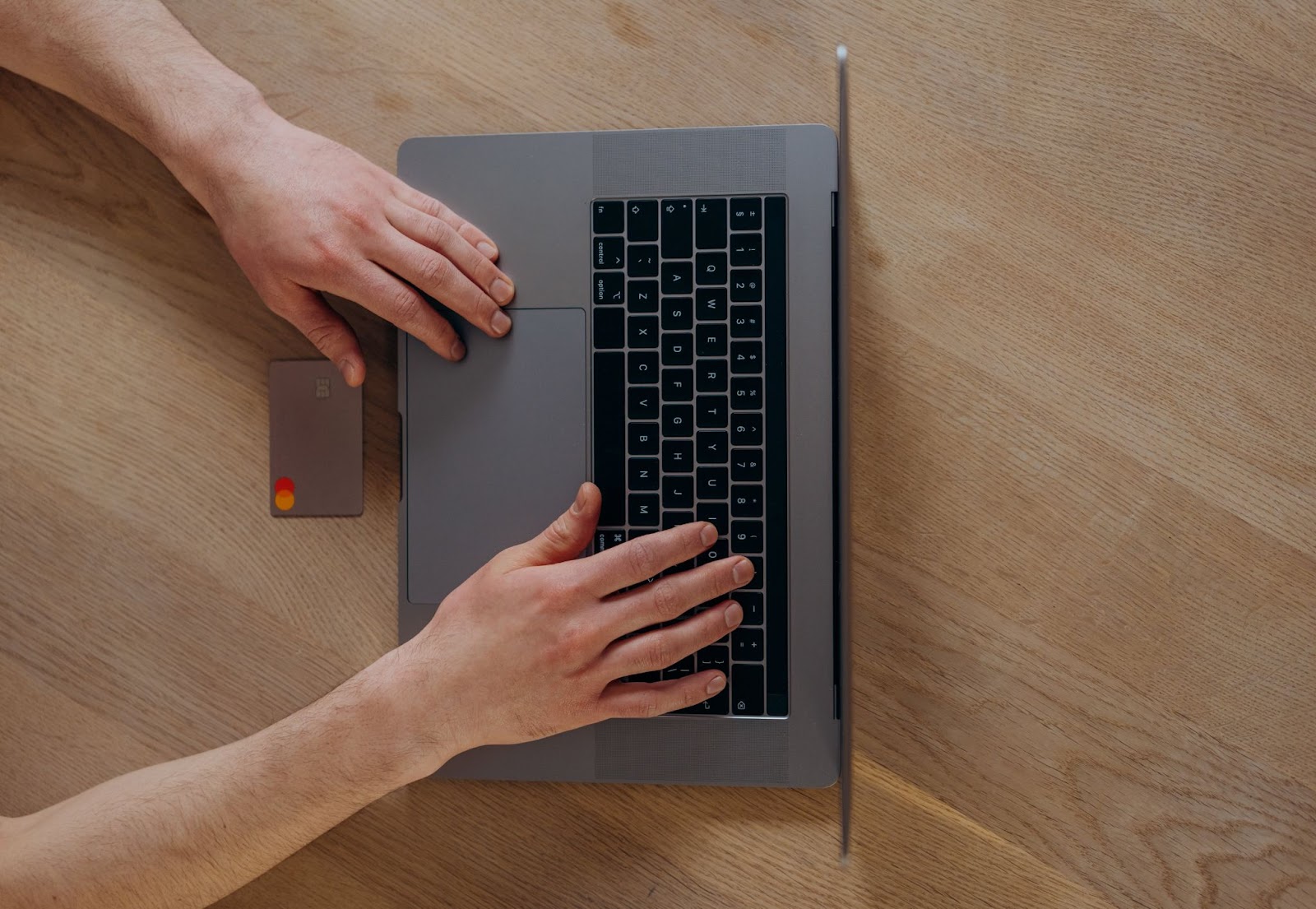 A bird’s eye view photo of a person typing their card numbers on a laptop keyboard