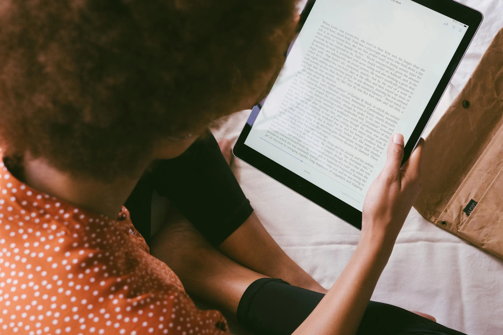 A bird's eye view photo of a person reading an e-book on their tablet