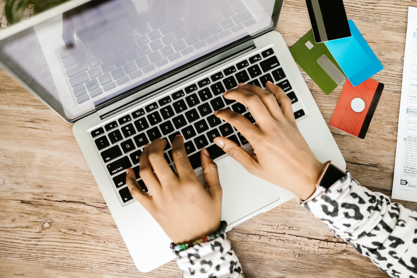 A bird's eye view photo of a person using a laptop with payment cards placed next to it