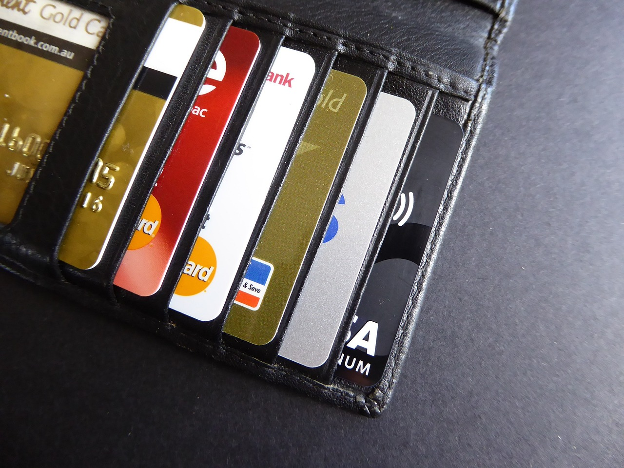 A close-up photo of payment cards inside a wallet placed on a black surface