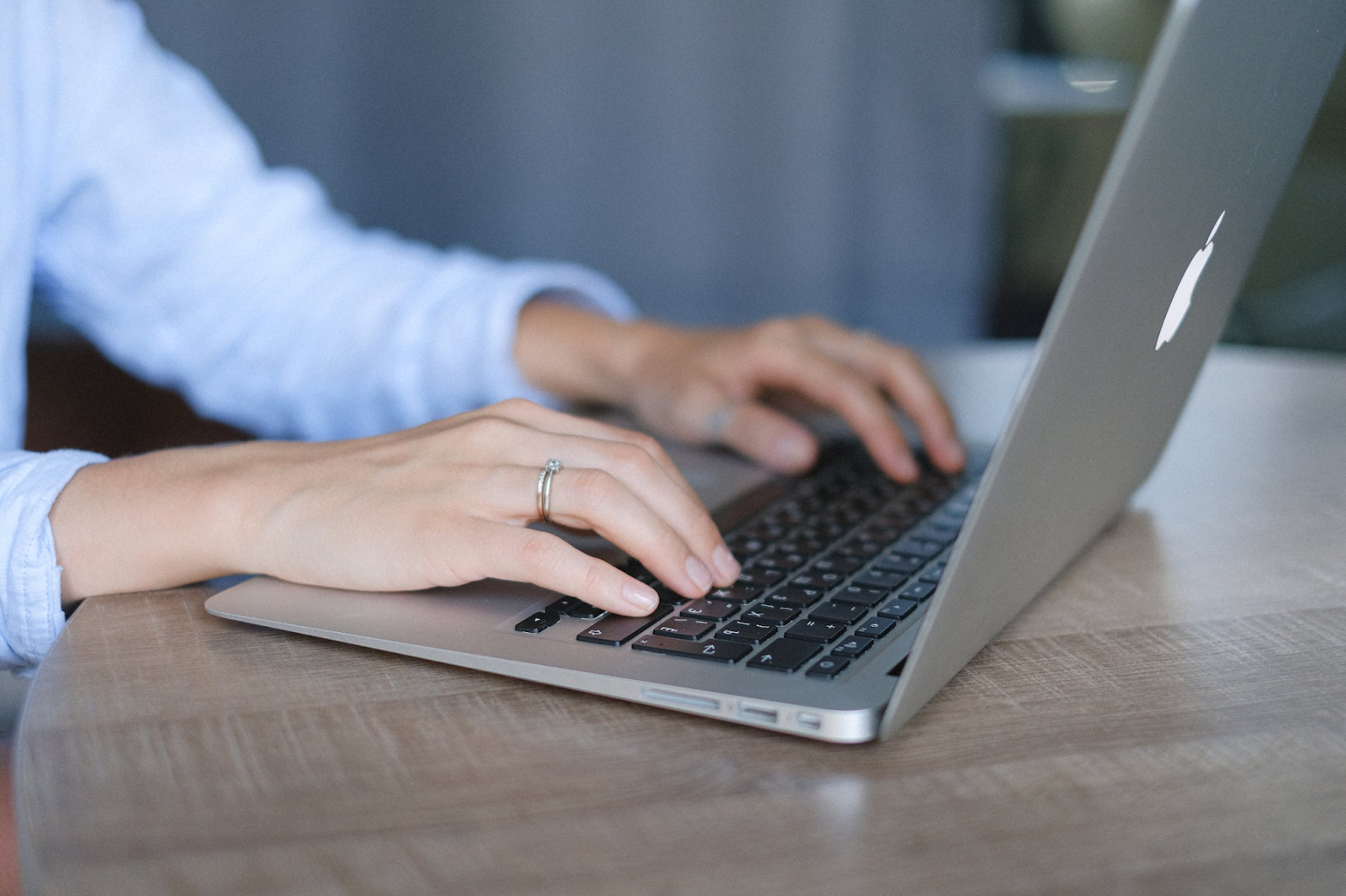 A close-up photo of a person using a laptop placed on a wooden table