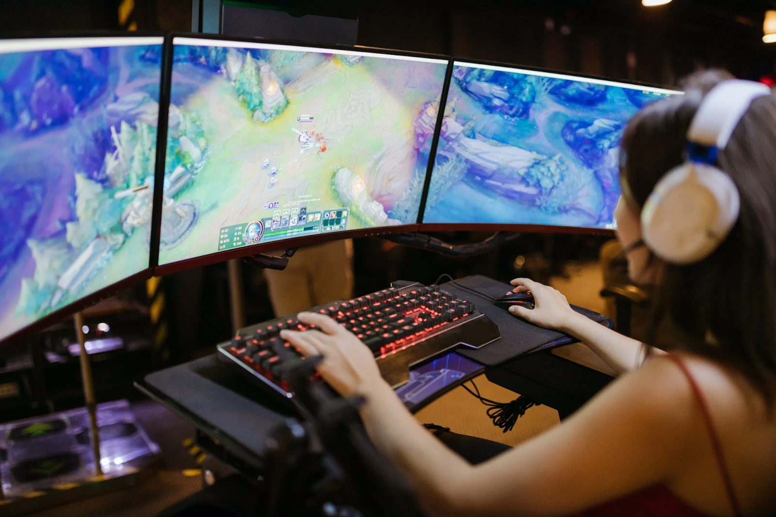 A photo of a young woman playing an online game on an ultrawide curved monitor