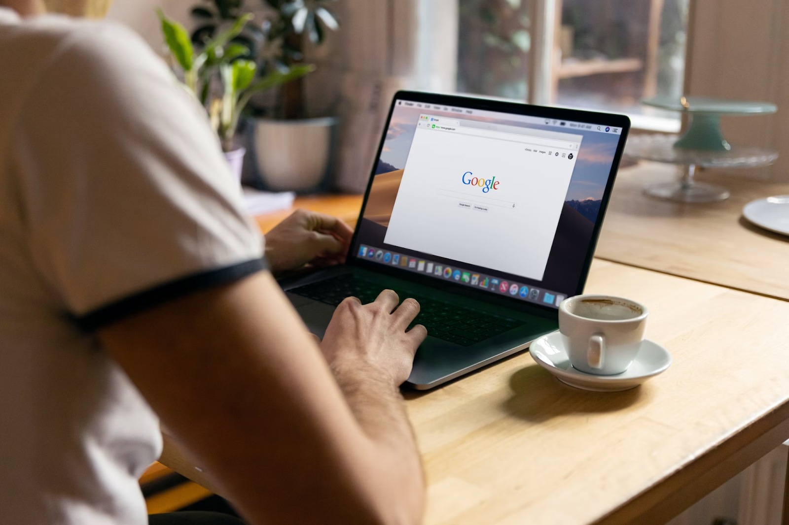 A photo of a person accessing the Google search engine via laptop placed on a wooden table