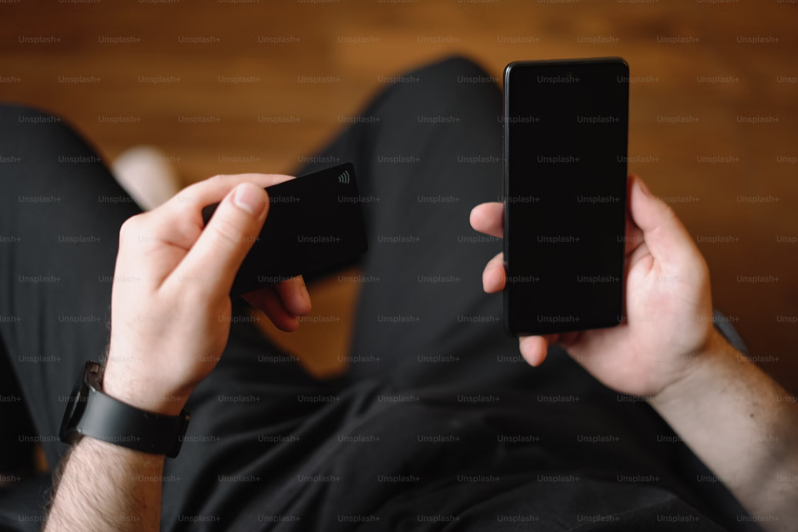 A photo of a man holding a phone in one hand and a payment card in another