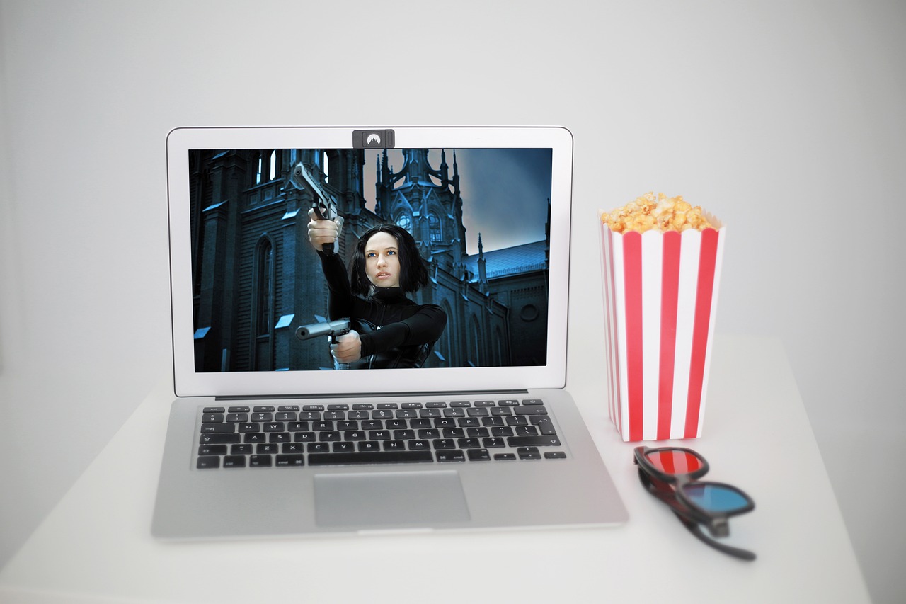 A photo of a laptop with a movie playing on the screen and popcorn on the side