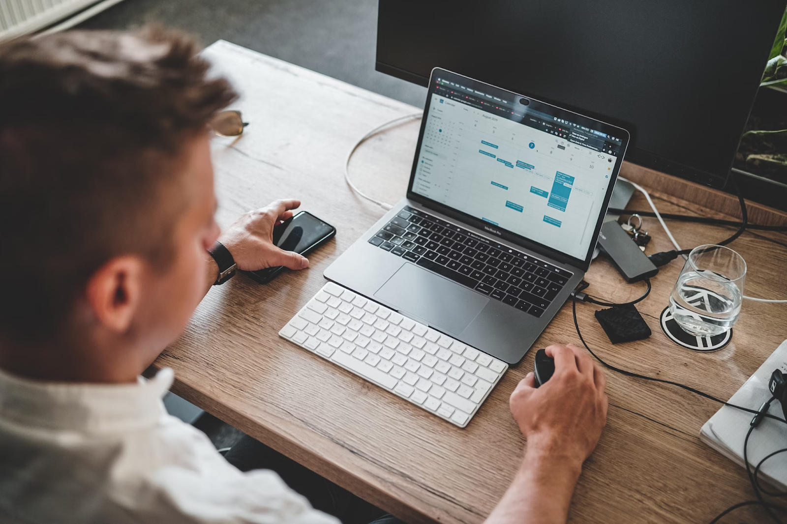 A bird’s eye view photo of a man using a MacBook on a work desk