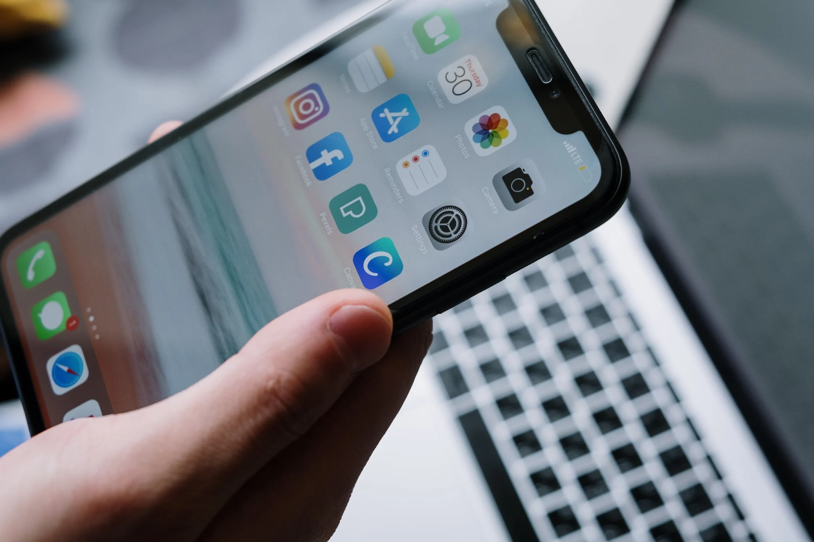 A close-up photo of a hand holding a turned-on iPhone