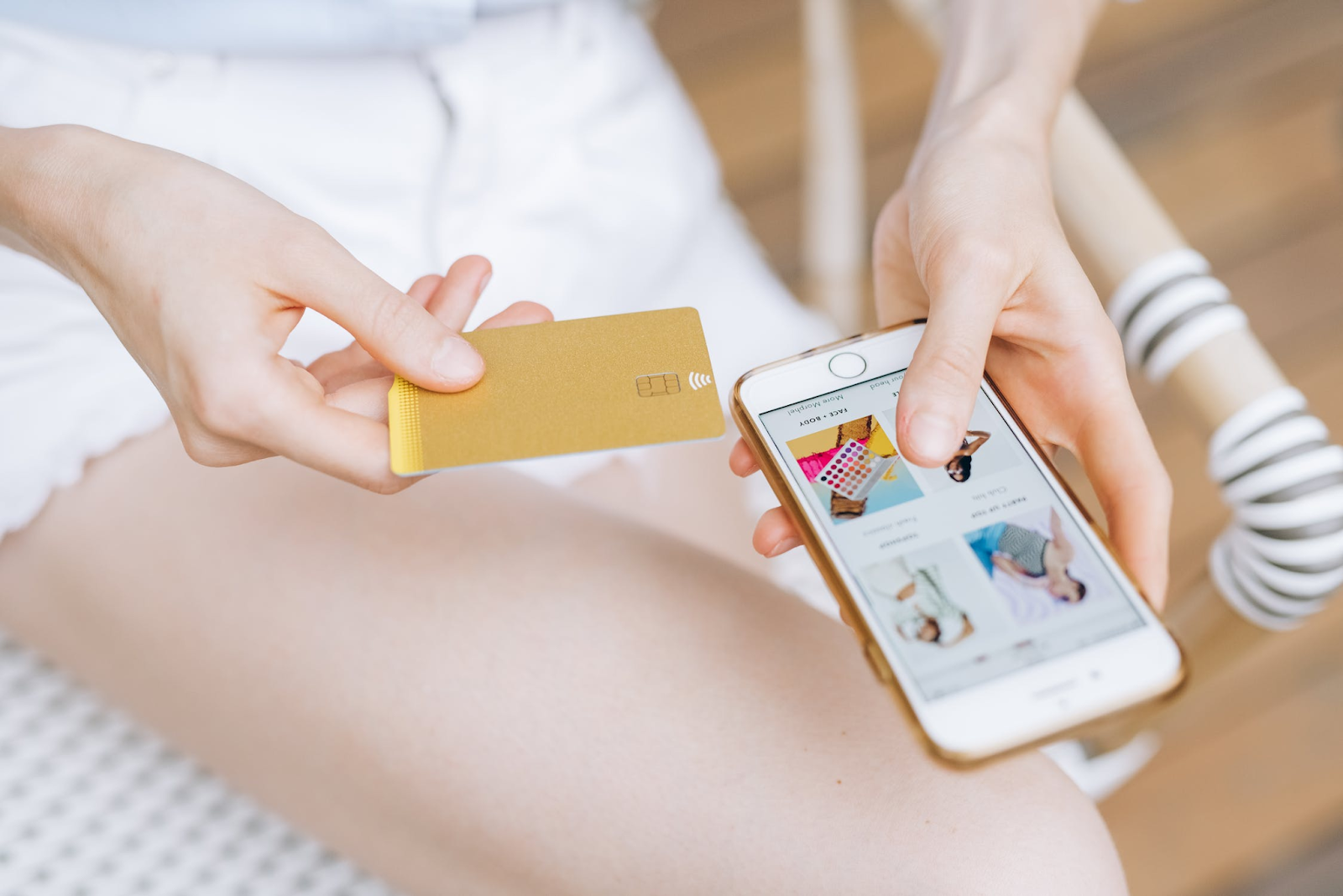 A photo of a woman holding a payment card to make an online payment on her phone