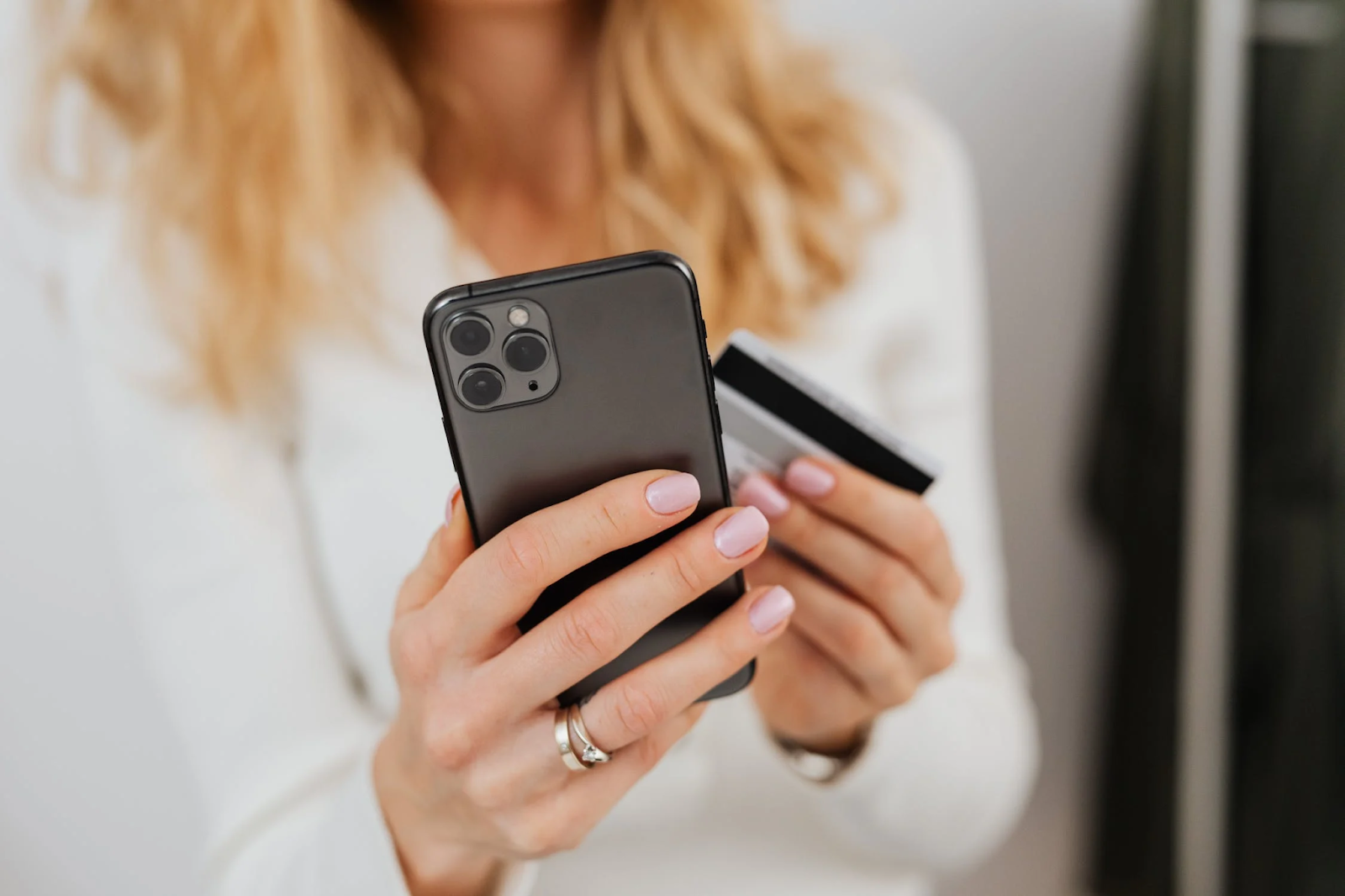 A photo of a woman holding an iPhone and a payment card in her hands