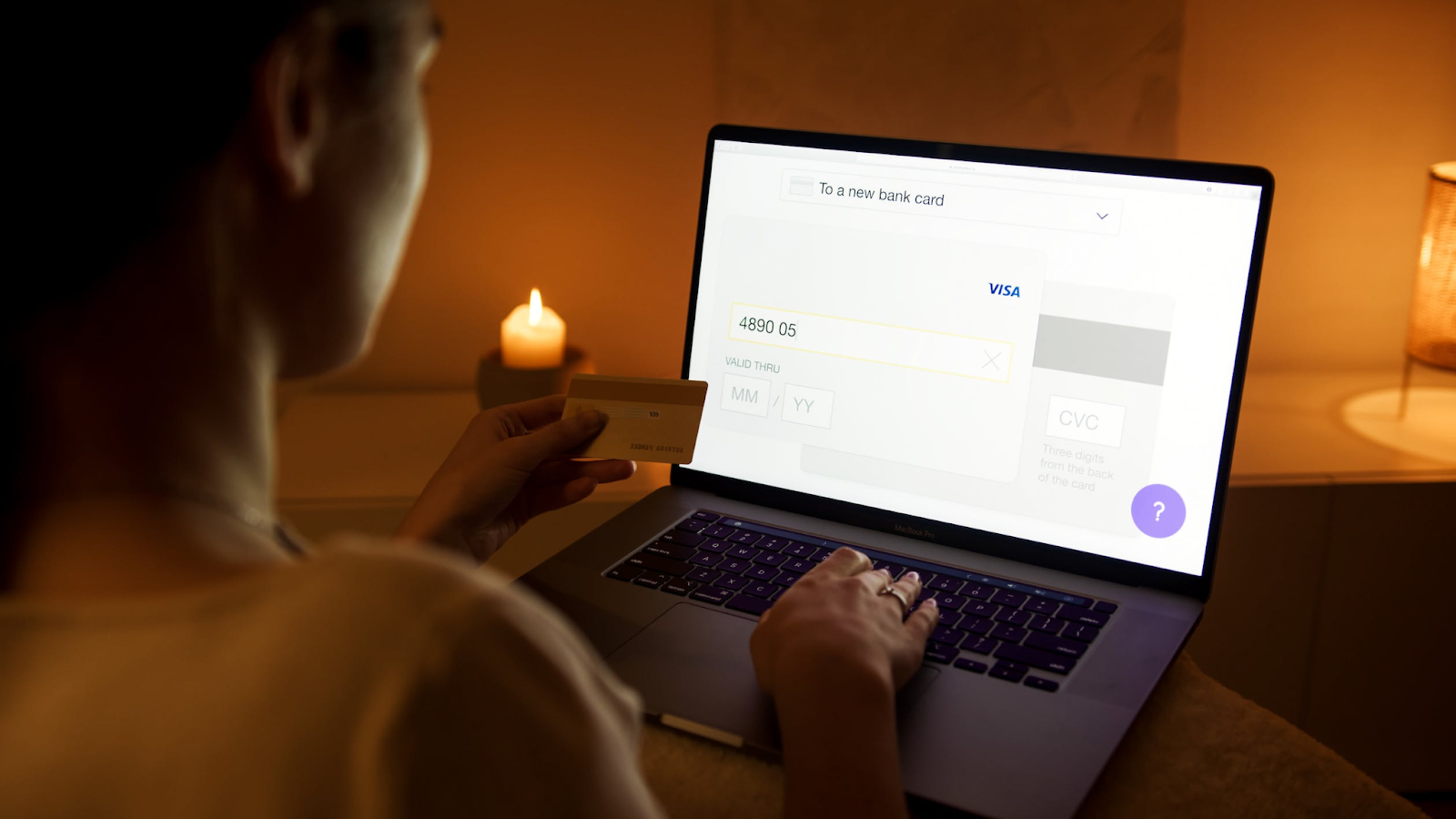 A photo of a woman typing in her payment card details on a laptop