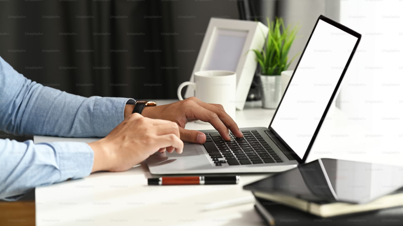 A photo of a person typing on a laptop placed on a white workspace