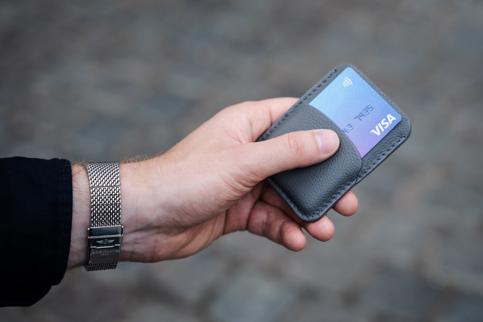 A close-up photo of a hand holding a cardholder with a Visa card in it