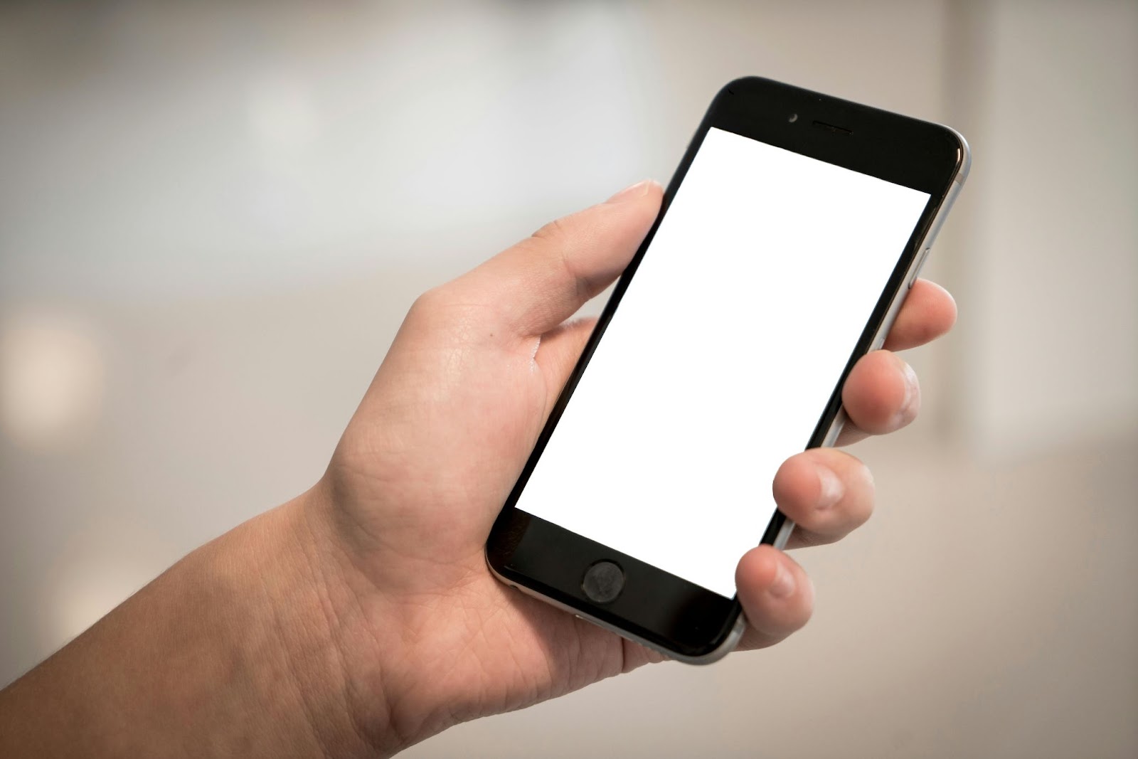 A photo of a person using an iPhone displaying a white screen