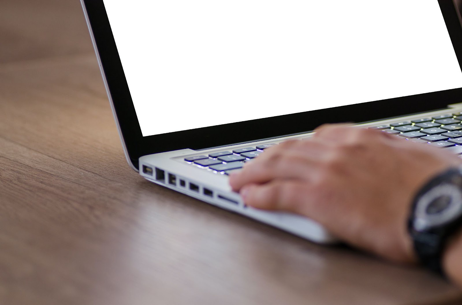 A close-up photo of a person using a Mac laptop displaying a white screen