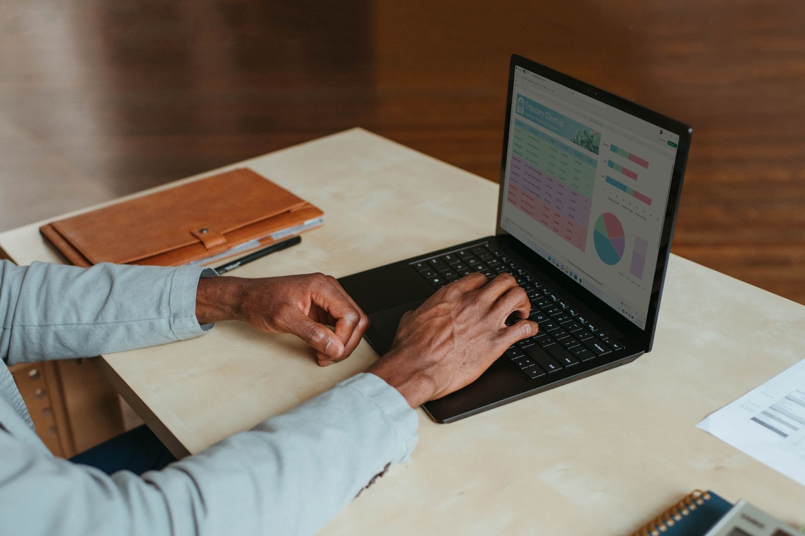 A photo of a person sitting at a desk and viewing charts on a laptop