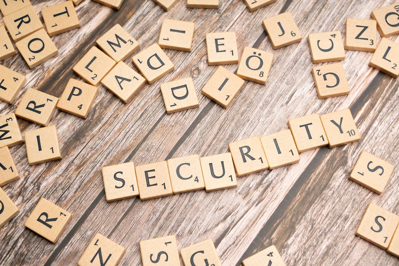 A photo of square letter tiles scattered on a wooden surface, with some of them arranged to spell out the word "SECURITY"