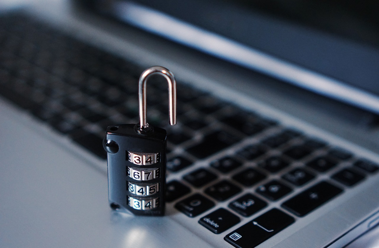 A close-up photo of an unlocked black combination lock placed on top of a laptop keyboard