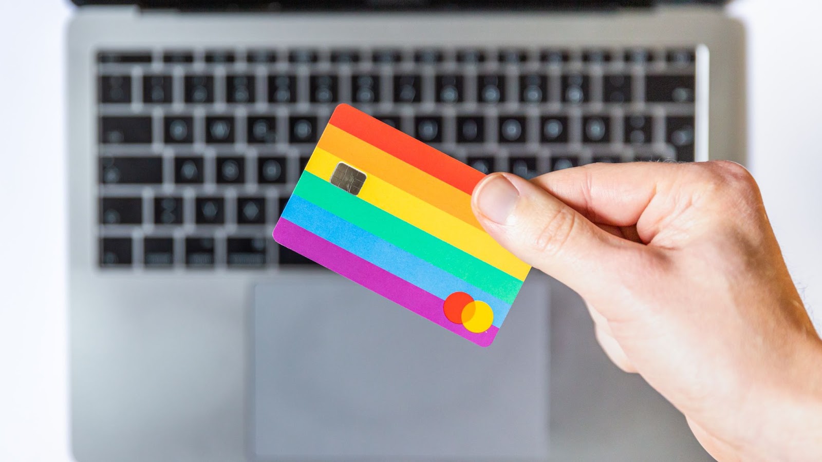 A photo of a person holding a payment card in front of a laptop