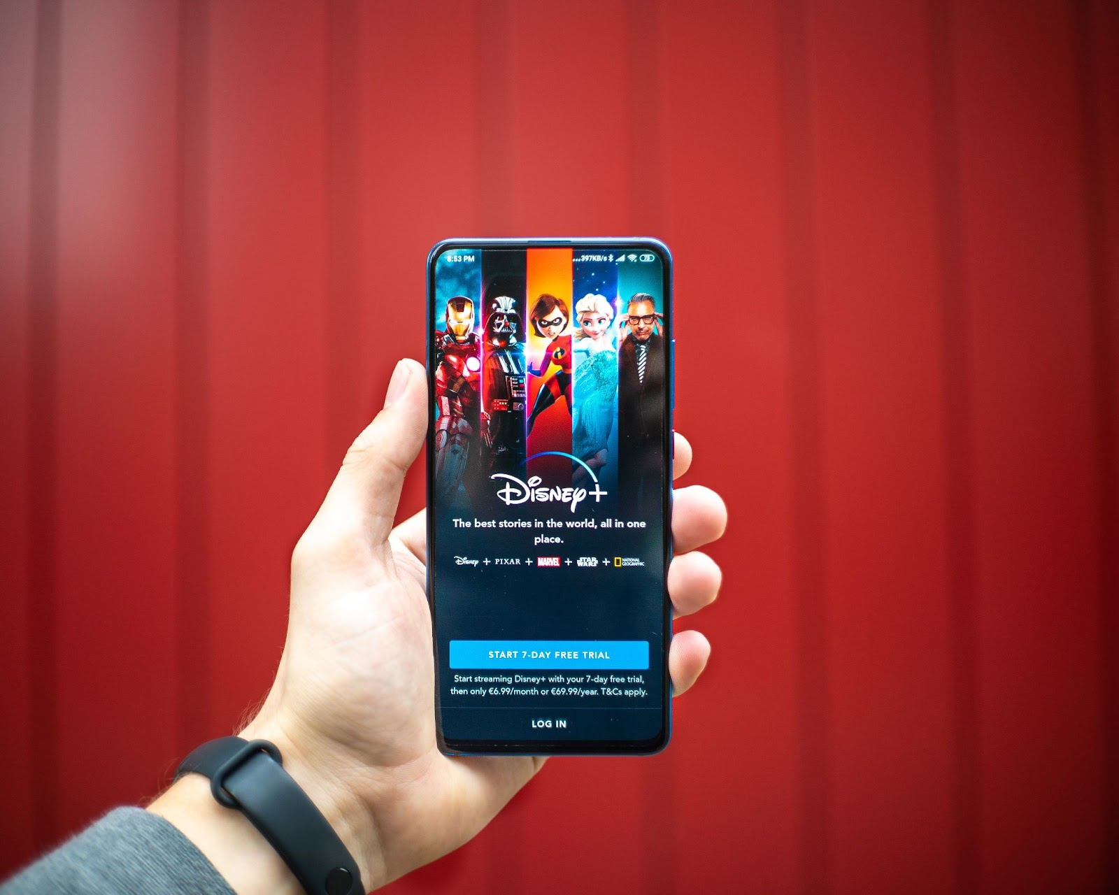 A photo of a person holding a smartphone that displays the Disney Plus subscription screen