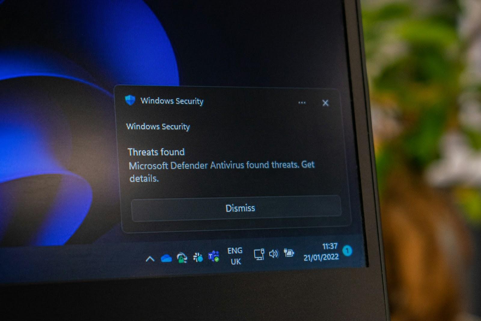 A close-up photo of a computer monitor showing a Microsoft Defender Antivirus "Threats found" alert 