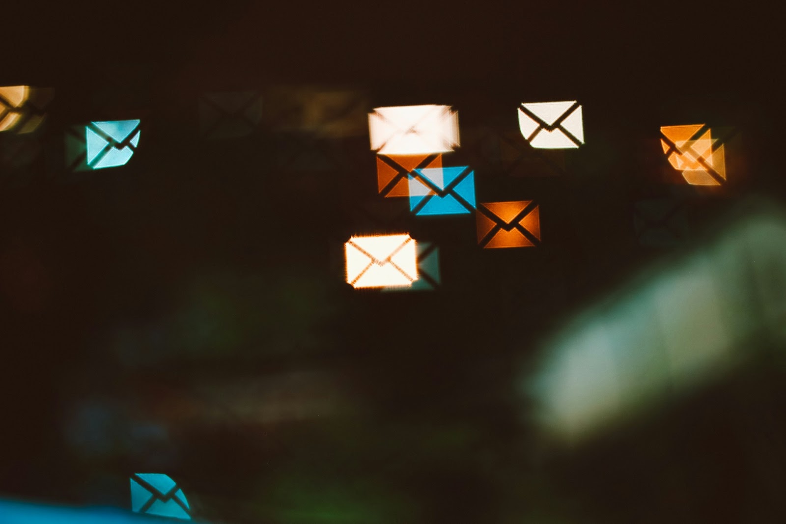An image showing floating email icons in blue, orange, and white against a dark background