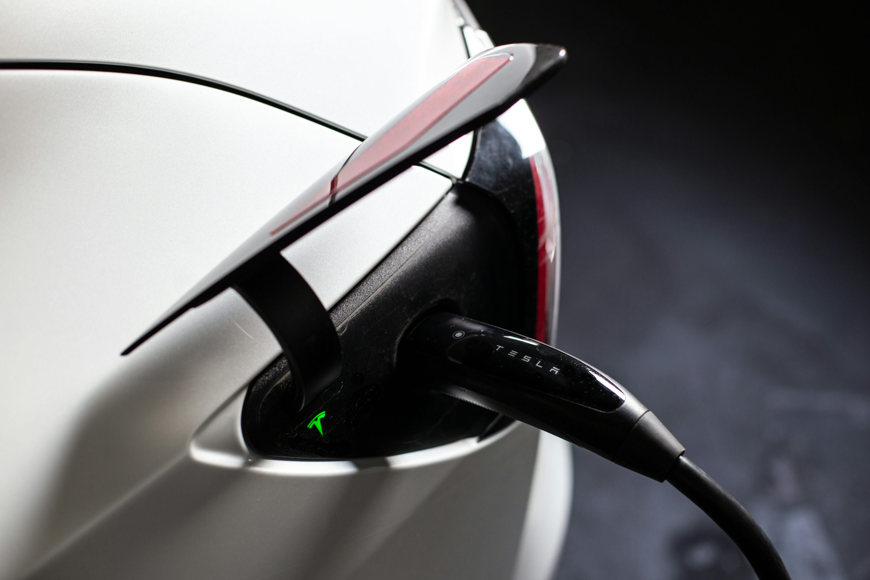 Electric vehicle connected to a home charging station in a garage.
