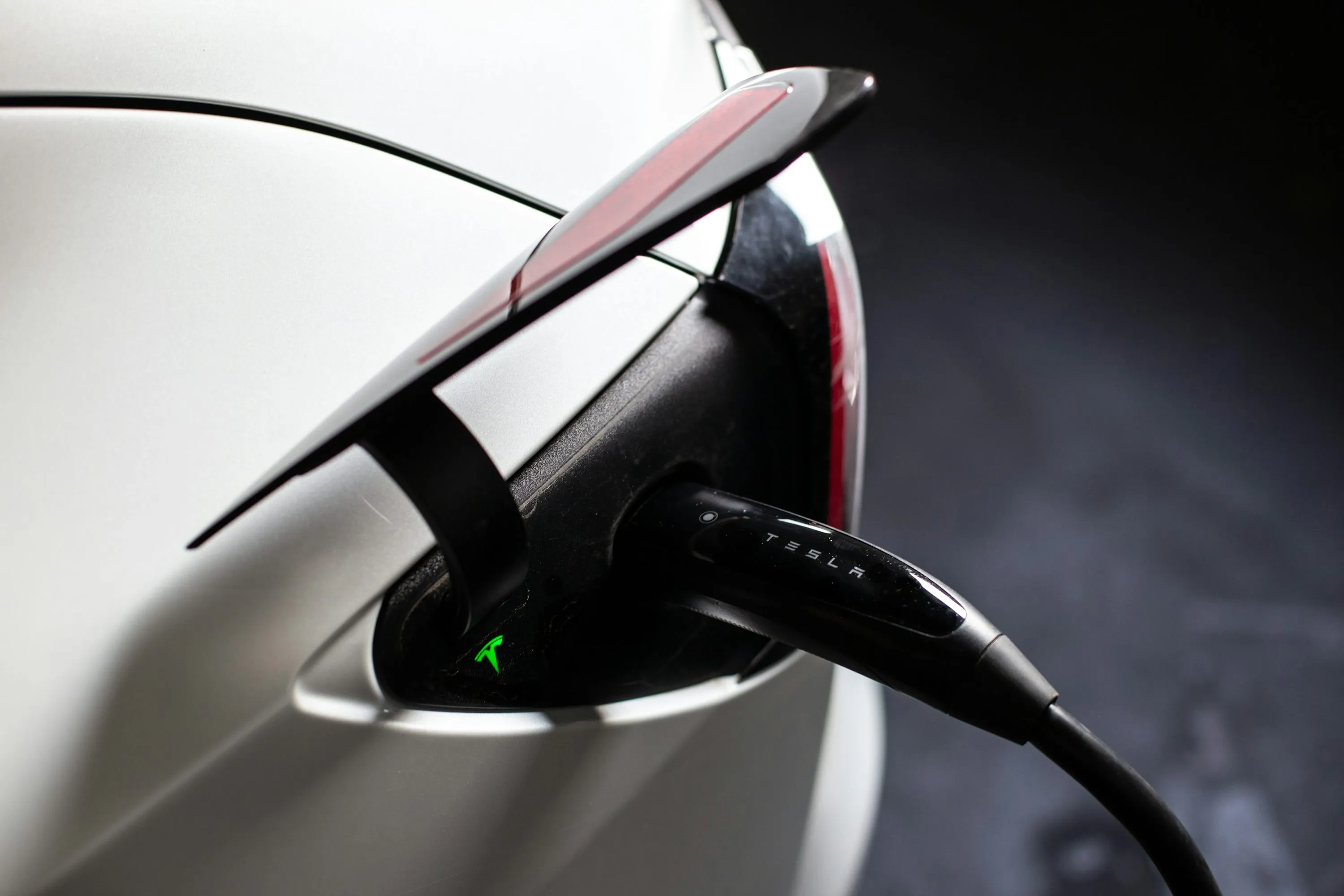 Electric vehicle connected to a home charging station in a garage.