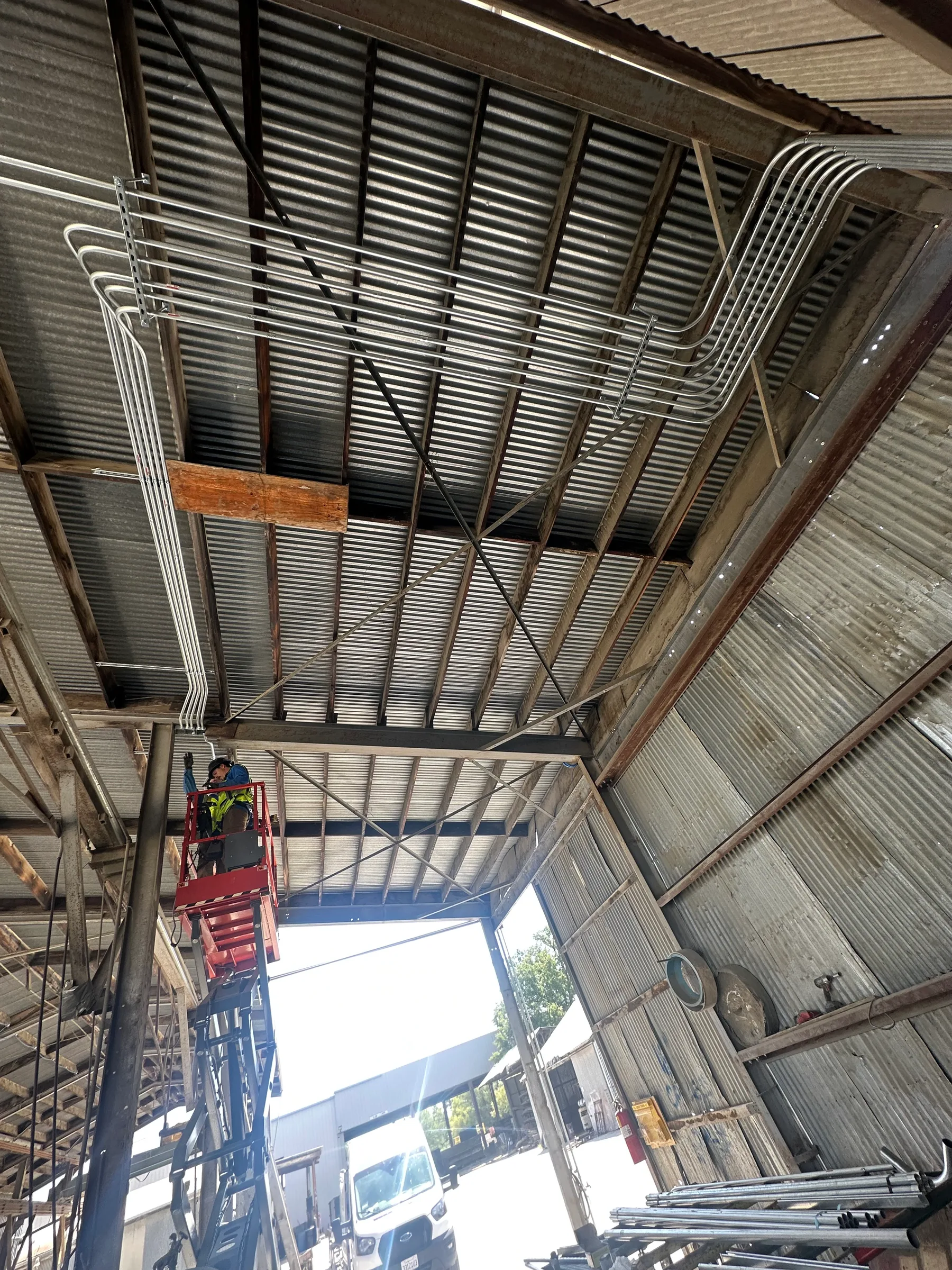 Completed overhead conduit and raceway retrofit with scissor lift inside the Oldcastle Infrastructure facility in Redding.