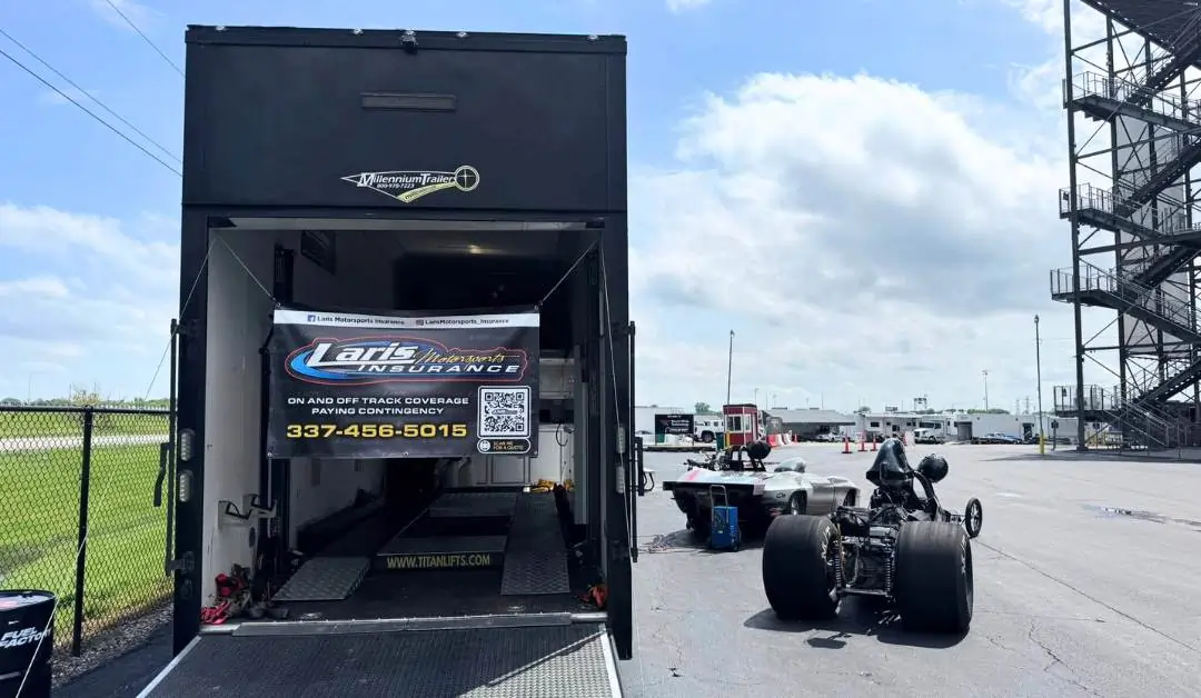 image of race team with car in front of race trailer