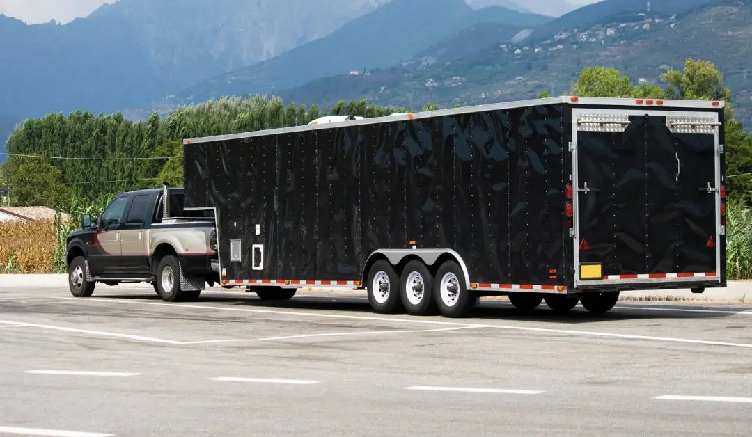 Black car trailer on a truck carrying a race car.