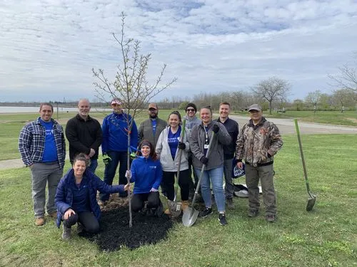 group of people standing in front of a newly planted tree