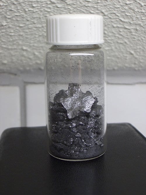 A small container filled with grey, metallic fragments of Boron