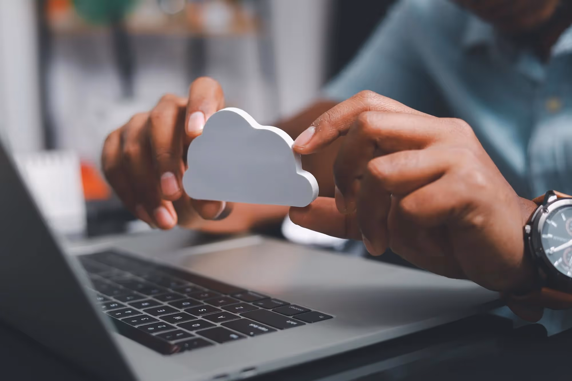 businessman in front of a laptop contemplating cloud migration with a cloud symbol in hands