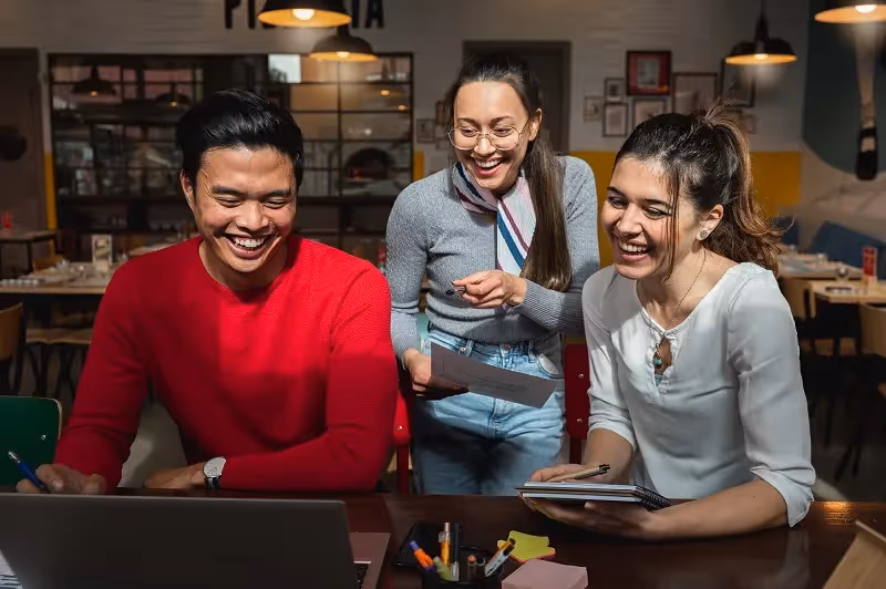 a happy group of office workers in front of a laptop 